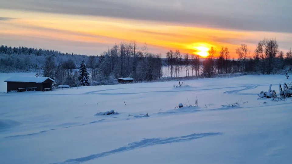 Nouseva aurinko valaisee lumista peltoa Pelkosenniemellä.