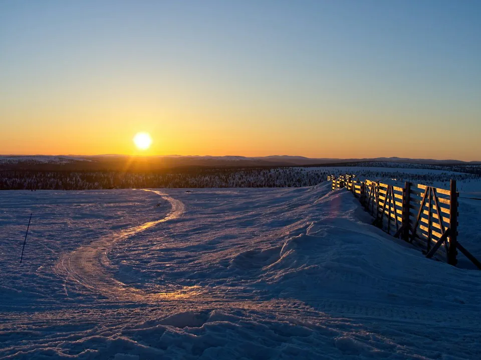 Aurinko valaisee Kaunispään sinisävyistä lumista tunturimaisemaa Saariselällä.